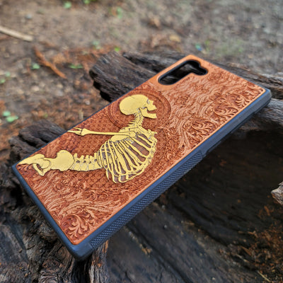Close-up of intricate Gothic skeleton engraving on hand-finished cherry wood phone case