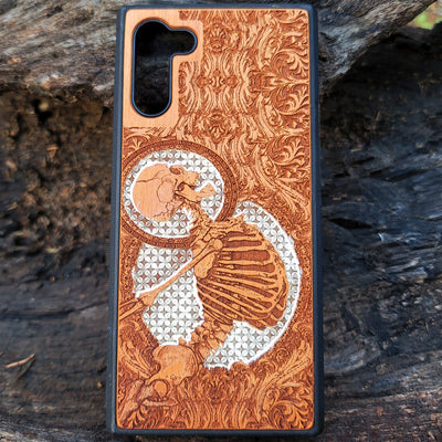 Gothic human skull with intricate details engraved on a wooden phone case, compatible with iPhone  and Samsung Galaxy S.