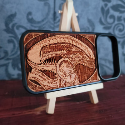 A wooden phone case with a detailed laser-engraved Alien Xenomorph design