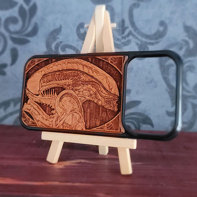 A wooden phone case with a detailed laser-engraved Alien Xenomorph design