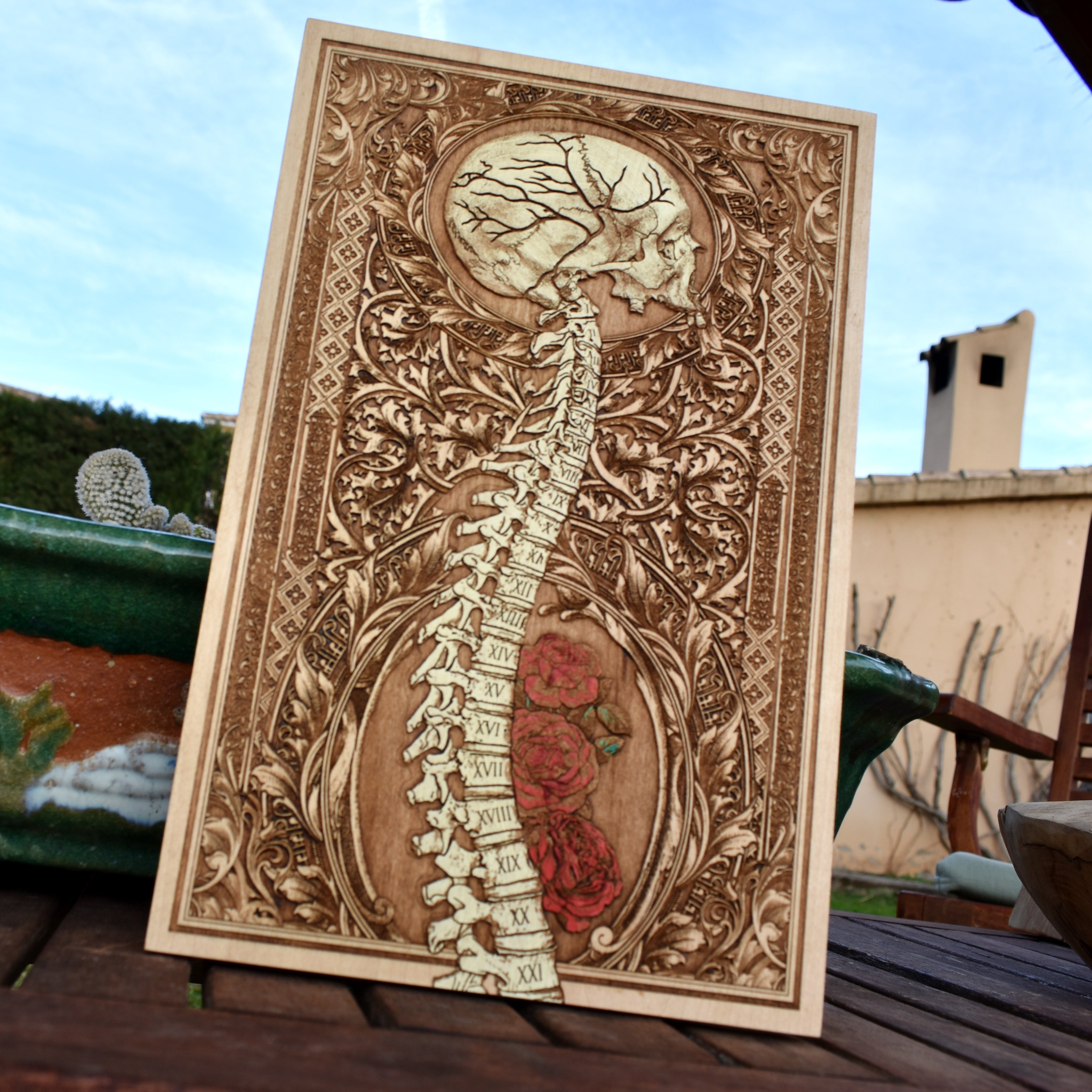 Hand-painted anatomical skull and spine artwork on engraved wood panel.