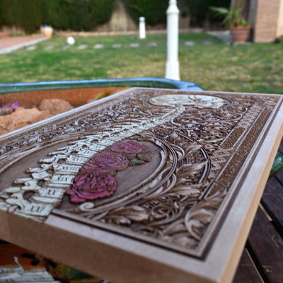 Macabre wood art featuring human skeleton spine, skull, and roses.