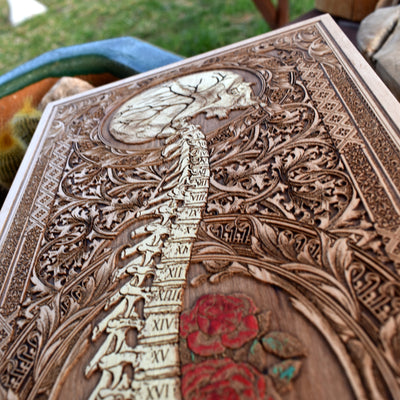 Engraved skull with numbered spine and floral details, gothic wood decor.