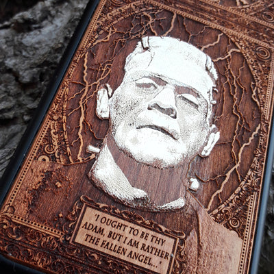 Laser-engraved Frankenstein's monster design on a wooden phone case, featuring the quote “I ought to be thy Adam, but I am rather the fallen angel...” Compatible with iPhone 16 and Samsung Galaxy S25.
