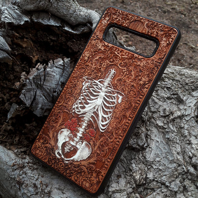 Laser-engraved anatomical human skeleton design on a wooden phone case, compatible with iPhone 16, iPhone 15, Galaxy S25, and more.