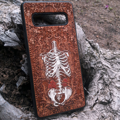 Laser-engraved anatomical human skeleton design on a wooden phone case, compatible with iPhone 16, iPhone 15, Galaxy S25, and more.