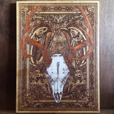 Rustic wood wall art featuring engraved deer skull with gothic styling.