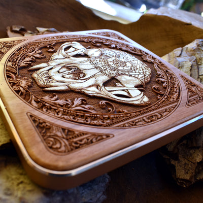 Wood wireless charger with engraved cat skull art, styled in a dark-themed workspace.