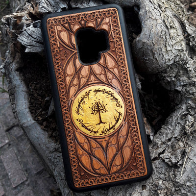 Collection of engraved wooden phone cases featuring unique designs: 'Ra Eye,' 'Red King Eye,' 'Ying Yang,' 'Aztec,' 'Celtic Tree,' 'Flower of Life,' 'Indie Hand,' and 'Tolkien.' Each case showcases intricate details on a natural wood finish, compatible with iPhone  and Samsung Galaxy S models. Stylish protection with symbolic artistry.
