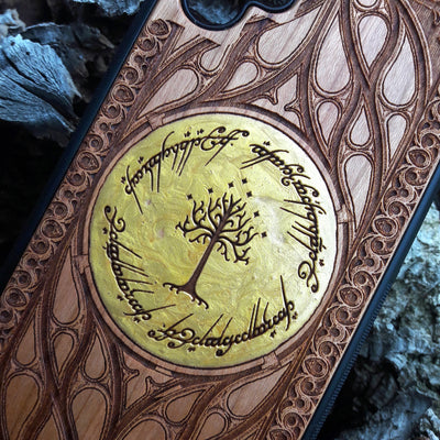 Collection of engraved wooden phone cases featuring unique designs: 'Ra Eye,' 'Red King Eye,' 'Ying Yang,' 'Aztec,' 'Celtic Tree,' 'Flower of Life,' 'Indie Hand,' and 'Tolkien.' Each case showcases intricate details on a natural wood finish, compatible with iPhone  and Samsung Galaxy S models. Stylish protection with symbolic artistry.