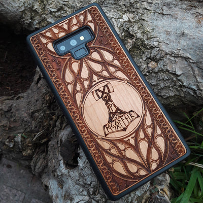 Eco friendly wood phone case carved with a beautiful carved Mjolnir the Hammer of Thor design. Quality sustainable wooden handcrafted and laser engraved covers.Available for: iPhone 11,12,13,14 Pro Max, Mini, Plus and Samsung Galaxy S20, S21, S22, Plus, Ultra, Note 20, Note 10