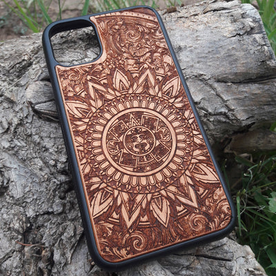 Intricately engraved wooden phone case featuring an Aztec calendar design with ornate details, crafted for durability and style. Compatible with iPhone  and Samsung Galaxy S models, this case combines cultural artistry with premium protection for your device.