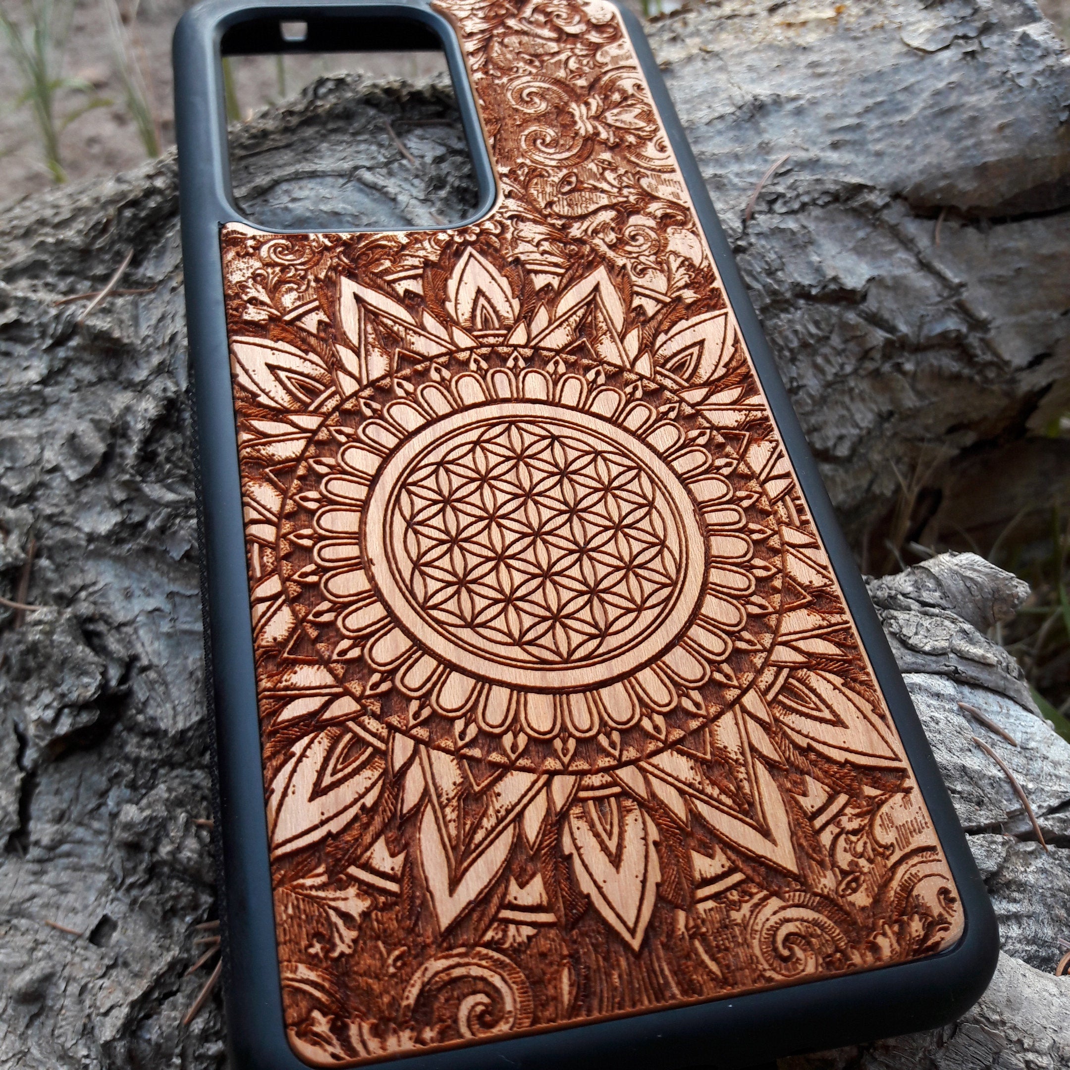 Wooden phone case featuring a detailed, laser-engraved Flower of Life design with intricate mandala patterns. Slim, durable, and compatible with iPhone 16, 15, 14, 13, 12, 11 Pro Max Mini and Samsung Galaxy S25, S24, S23, S22, S21, S20 Ultra Plus, Note 20. Perfect for those who appreciate sacred geometry and natural aesthetics.