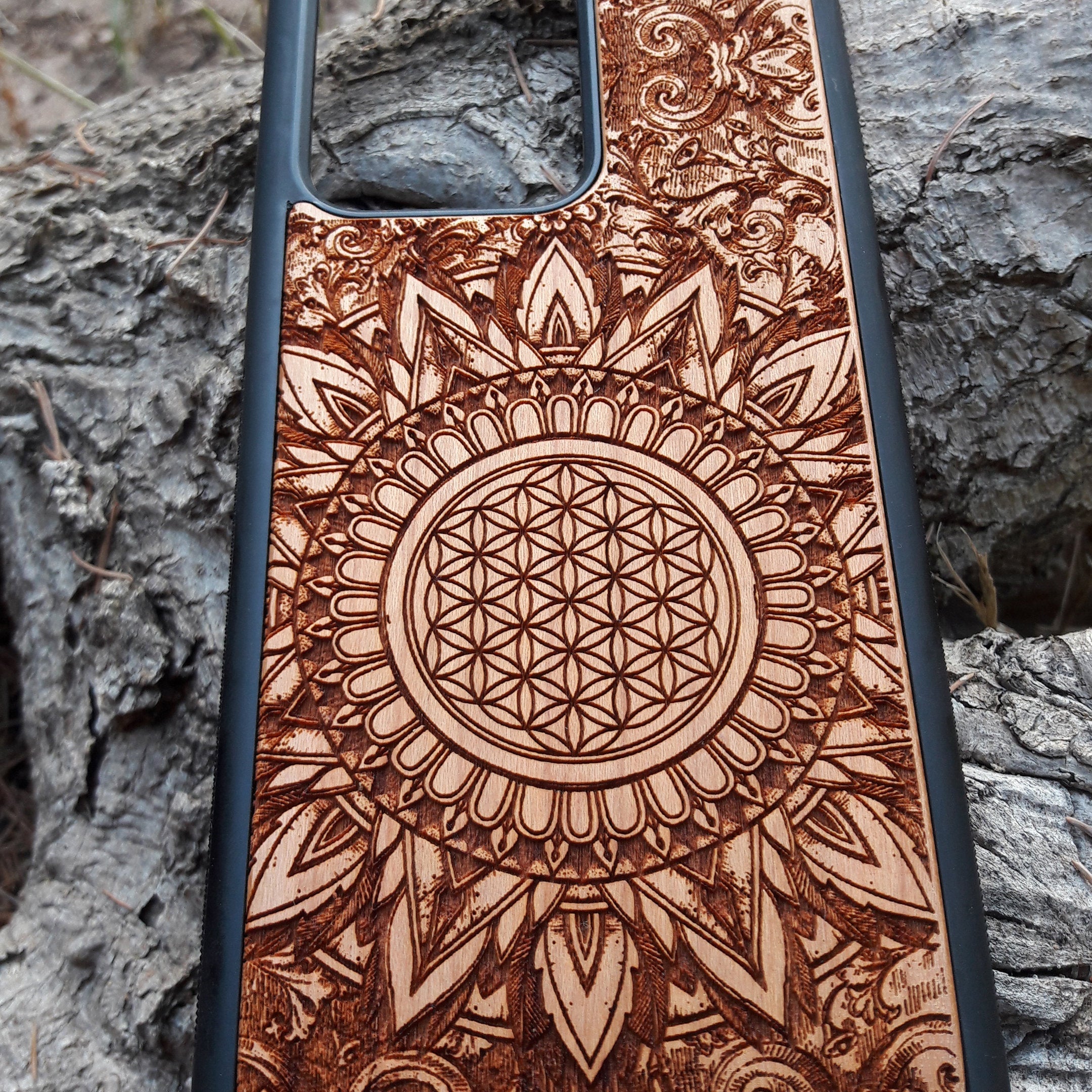 Wooden phone case featuring a detailed, laser-engraved Flower of Life design with intricate mandala patterns. Slim, durable, and compatible with iPhone 16, 15, 14, 13, 12, 11 Pro Max Mini and Samsung Galaxy S25, S24, S23, S22, S21, S20 Ultra Plus, Note 20. Perfect for those who appreciate sacred geometry and natural aesthetics.