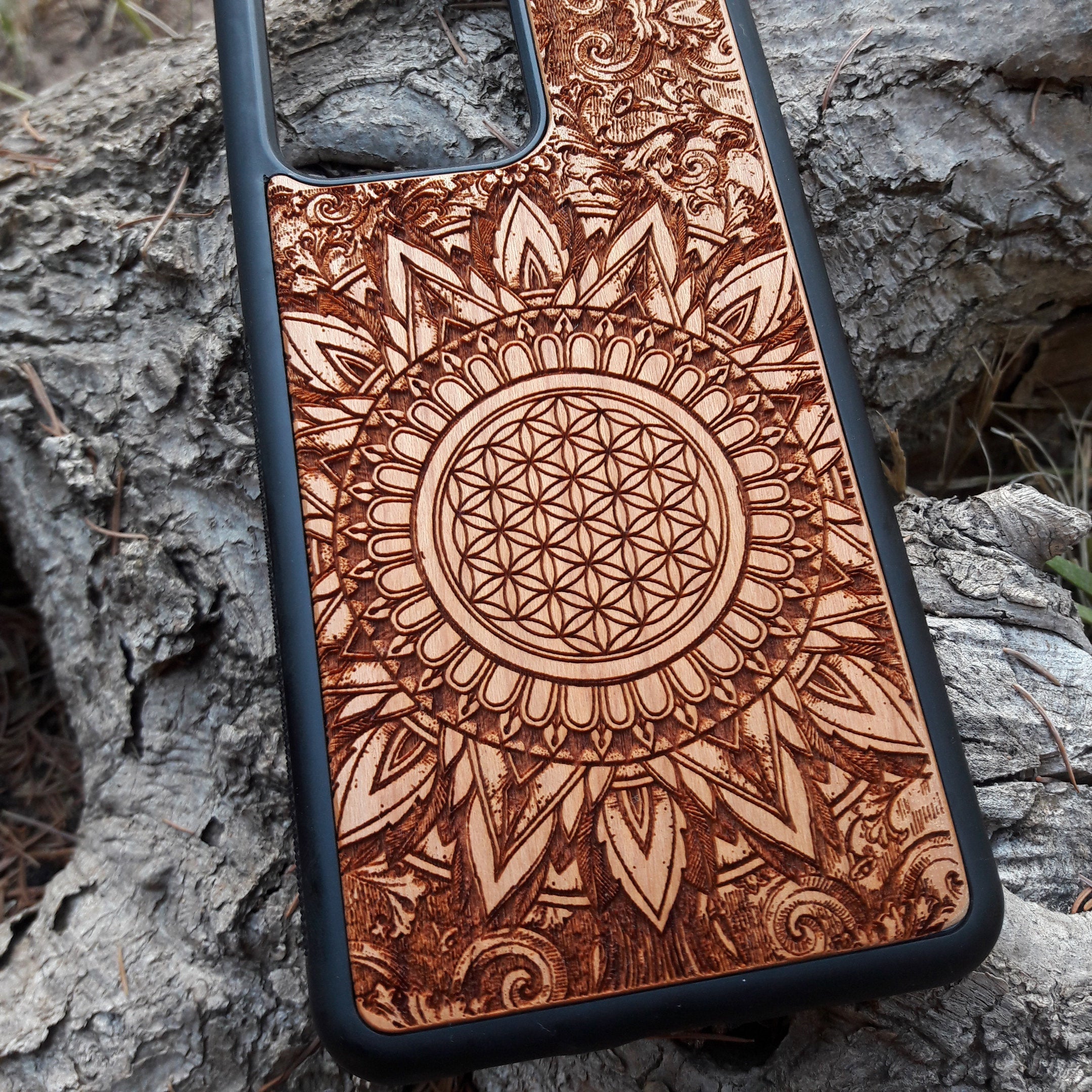 Wooden phone case featuring a detailed, laser-engraved Flower of Life design with intricate mandala patterns. Slim, durable, and compatible with iPhone 16, 15, 14, 13, 12, 11 Pro Max Mini and Samsung Galaxy S25, S24, S23, S22, S21, S20 Ultra Plus, Note 20. Perfect for those who appreciate sacred geometry and natural aesthetics.