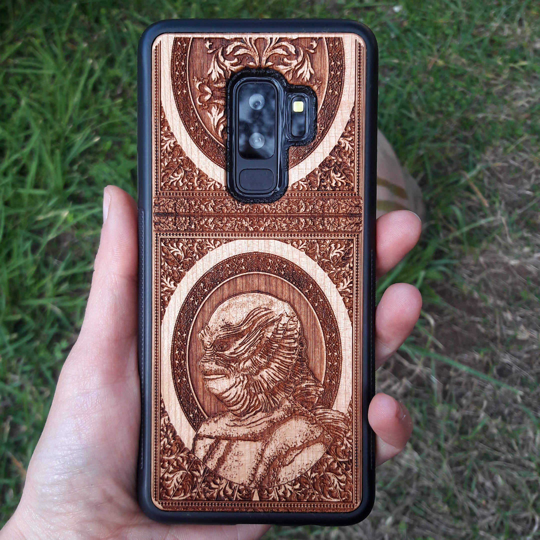 Wooden phone case with intricate carving of the Creature from the Black Lagoon design, crafted for iPhone 16, Samsung Galaxy S25. Perfect for horror fans and collectors, offering premium protection and gothic style.