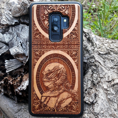 Wooden phone case with intricate carving of the Creature from the Black Lagoon design, crafted for iPhone 16, Samsung Galaxy S25. Perfect for horror fans and collectors, offering premium protection and gothic style.