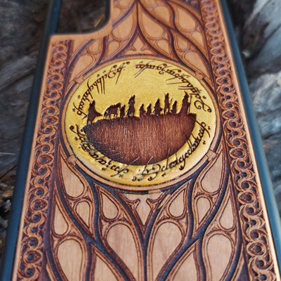 Hand-painted Lord of the Rings wood phone case featuring the Fellowship of the Ring silhouette surrounded by Elvish script and intricate patterns. The golden accent highlights the design, making it a unique and artistic piece. Laser-engraved for durability, this case is compatible with iPhone , 15, 14, 13, 12, 11, Pro Max, Mini, and Samsung Galaxy S, S24, S23, S22, S21, S20 Ultra, Plus, Note 20. A perfect accessory for Tolkien fans seeking style and protection.