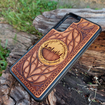 Hand-painted Lord of the Rings wood phone case featuring the Fellowship of the Ring silhouette surrounded by Elvish script and intricate patterns. The golden accent highlights the design, making it a unique and artistic piece. Laser-engraved for durability, this case is compatible with iPhone , 15, 14, 13, 12, 11, Pro Max, Mini, and Samsung Galaxy S, S24, S23, S22, S21, S20 Ultra, Plus, Note 20. A perfect accessory for Tolkien fans seeking style and protection.
