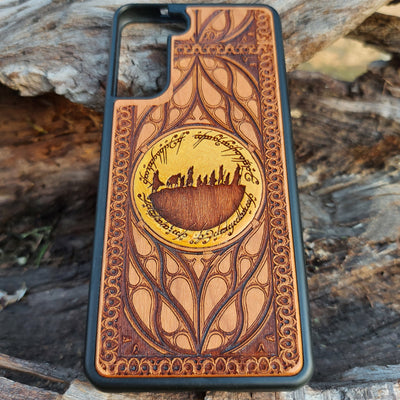 Hand-painted Lord of the Rings wood phone case featuring the Fellowship of the Ring silhouette surrounded by Elvish script and intricate patterns. The golden accent highlights the design, making it a unique and artistic piece. Laser-engraved for durability, this case is compatible with iPhone , 15, 14, 13, 12, 11, Pro Max, Mini, and Samsung Galaxy S, S24, S23, S22, S21, S20 Ultra, Plus, Note 20. A perfect accessory for Tolkien fans seeking style and protection.