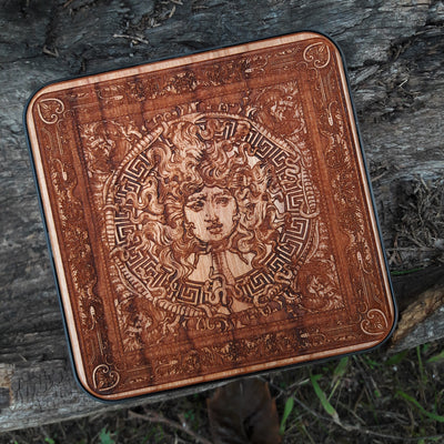 Close-up of detailed Medusa face painted on wood wireless charger.