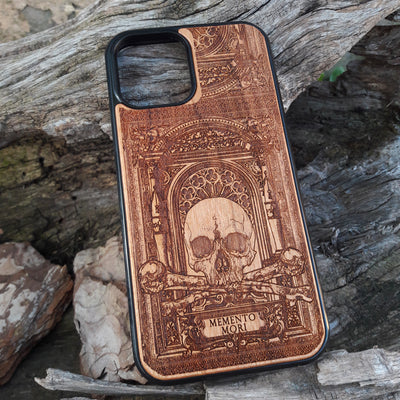 Laser-engraved Memento Mori wood phone case featuring a skull, crossbones, and intricate Gothic patterns with "Memento Mori" text for iPhone  and Samsung Galaxy S. Perfect for Gothic and philosophical design lovers.