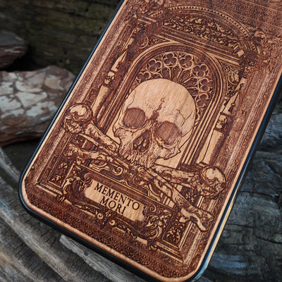 Laser-engraved Memento Mori wood phone case featuring a skull, crossbones, and intricate Gothic patterns with "Memento Mori" text for iPhone  and Samsung Galaxy S. Perfect for Gothic and philosophical design lovers.