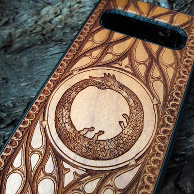 Eco friendly wood phone case carved with a beautiful Ouroboros design. Celtic Triskelion Spiral wood phone case with laser-engraved design for iPhone & Samsung Galaxy. Compatible with iPhone , 15, 14, 13, 12, 11 Pro Max Mini & Samsung Galaxy S, S24, S23, S22, S21, S20 Ultra Plus Note 20. Unique and durable.
