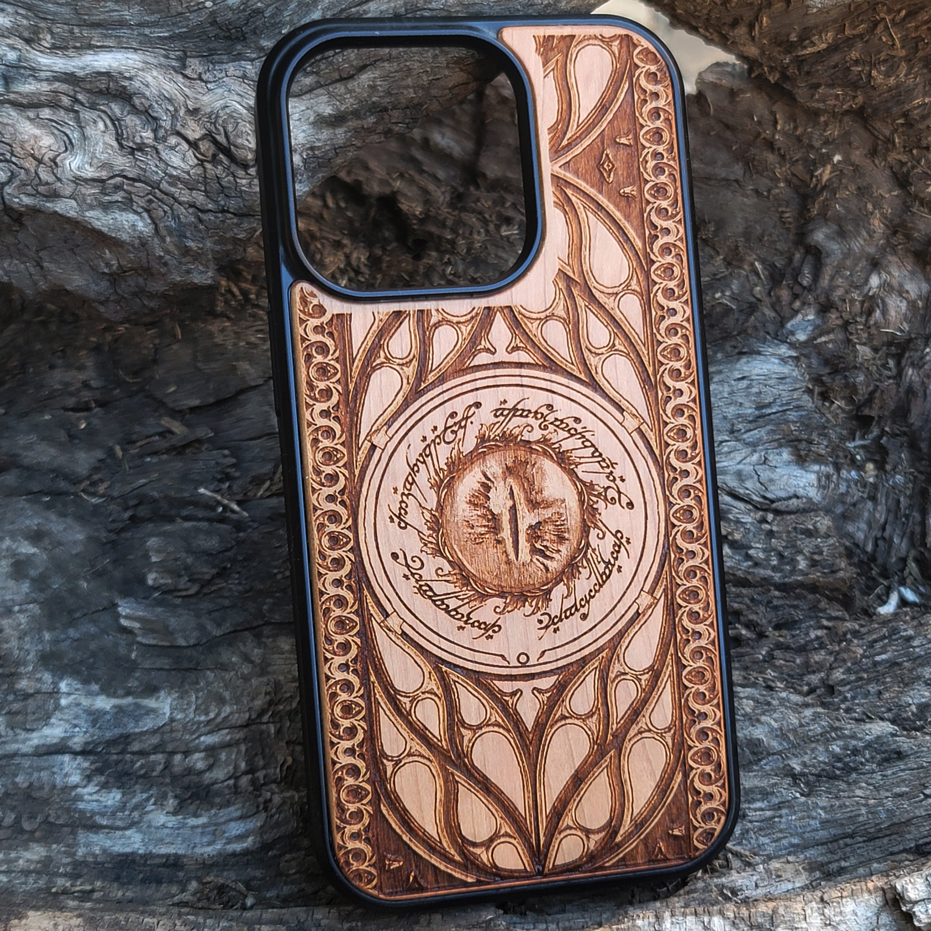 Lord of the Rings wood phone case featuring the Eye of Sauron surrounded by Elvish script and intricate, elegant patterns. Laser-engraved for durability and unique artistry, this case is compatible with iPhone 16, 15, 14, 13, 12, 11, Pro Max, Mini, and Samsung Galaxy S25, S24, S23, S22, S21, S20 Ultra, Plus, Note 20. A stunning and protective accessory for Tolkien fans.