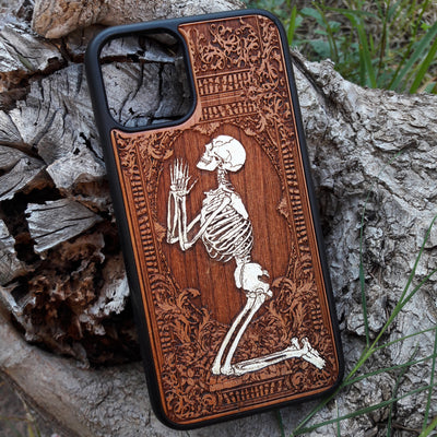Hand-painted wooden phone case featuring a laser-engraved gothic praying skeleton design on cherrywood. Compatible with iPhone -11 Pro Max and Galaxy S-S20 models.