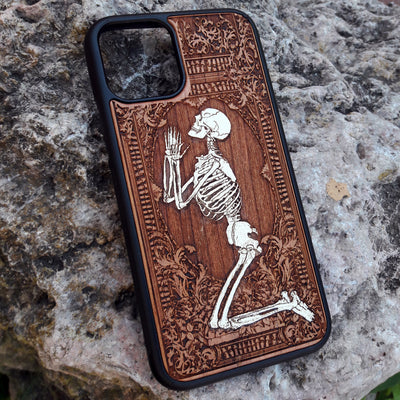 Hand-painted wooden phone case featuring a laser-engraved gothic praying skeleton design on cherrywood. Compatible with iPhone -11 Pro Max and Galaxy S-S20 models.