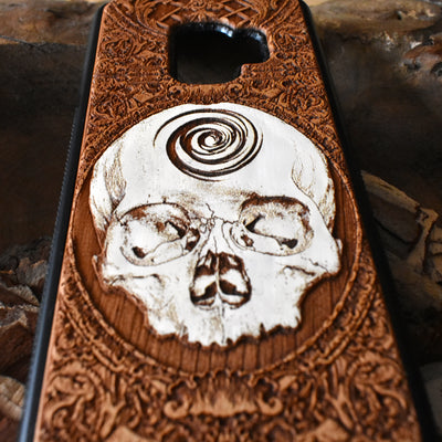 Laser-engraved skull art on a wooden phone case, compatible with iPhone 16, iPhone 15, Galaxy S25, and more.