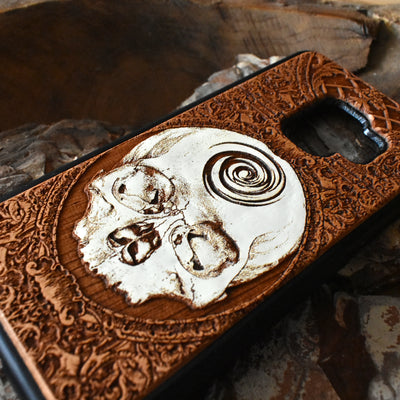 Laser-engraved skull art on a wooden phone case, compatible with iPhone 16, iPhone 15, Galaxy S25, and more.