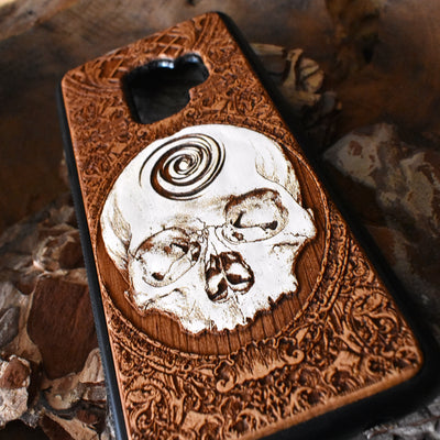 Laser-engraved skull art on a wooden phone case, compatible with iPhone 16, iPhone 15, Galaxy S25, and more.