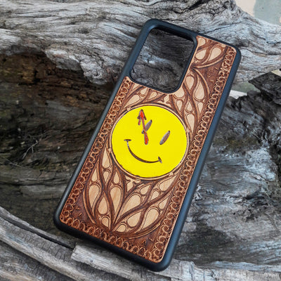 Wooden phone case for iPhone and Samsung Galaxy featuring the 'Smiley' symbol from the Watchmen saga, laser-engraved for a unique touch. Compatible with iPhone 15, 14, 13, 12, 11 Pro Max Mini and Samsung Galaxy S24, S23, S22, S21, S20 Ultra Plus Note 20. Slim, durable, and stylish—order now to make a statement!