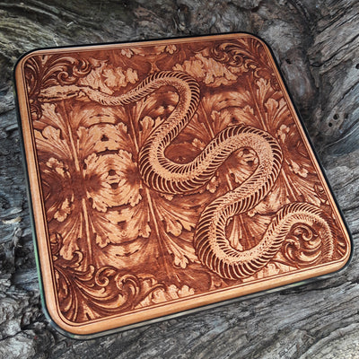 Close-up of intricate skeleton snake engraving on wood charging pad.