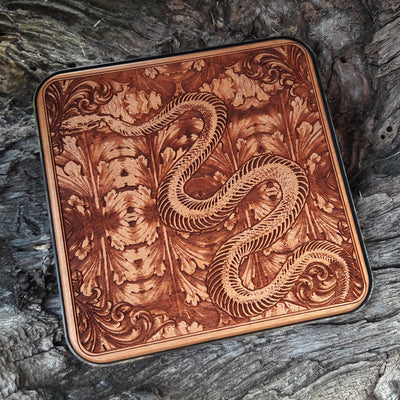 Handmade wireless charger with dark skeleton snake engraving.