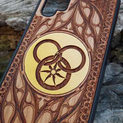 Wooden phone case featuring a detailed Wheel of Time-inspired design, showcasing intricate engravings of the Aes Sedai symbol and runes. The laser-engraved design captures the essence of Robert Jordan's iconic fantasy series. Compatible with iPhone , 15, 14, 13, 12, 11 Pro Max Mini, and Samsung Galaxy S, S24, S23, S22, S21, S20 Ultra, Plus, Note 20. A perfect, durable accessory for fans of the Wheel of Time series, blending art and protection.