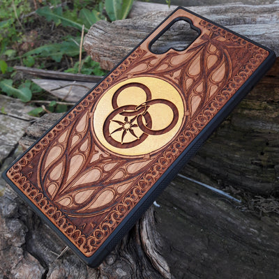 Wooden phone case featuring a detailed Wheel of Time-inspired design, showcasing intricate engravings of the Aes Sedai symbol and runes. The laser-engraved design captures the essence of Robert Jordan's iconic fantasy series. Compatible with iPhone , 15, 14, 13, 12, 11 Pro Max Mini, and Samsung Galaxy S, S24, S23, S22, S21, S20 Ultra, Plus, Note 20. A perfect, durable accessory for fans of the Wheel of Time series, blending art and protection.