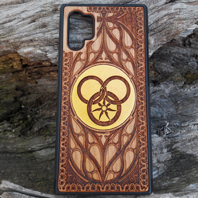 Wooden phone case featuring a detailed Wheel of Time-inspired design, showcasing intricate engravings of the Aes Sedai symbol and runes. The laser-engraved design captures the essence of Robert Jordan's iconic fantasy series. Compatible with iPhone , 15, 14, 13, 12, 11 Pro Max Mini, and Samsung Galaxy S, S24, S23, S22, S21, S20 Ultra, Plus, Note 20. A perfect, durable accessory for fans of the Wheel of Time series, blending art and protection.