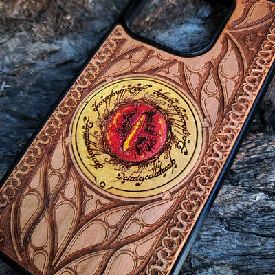 Hand-painted Lord of the Rings wood phone case featuring the Eye of Sauron with vibrant colors and laser-engraved Elvish script. Crafted with intricate detailing for durability and elegance, this case is compatible with iPhone , 15, 14, 13, 12, 11, Pro Max, Mini, and Samsung Galaxy S, S24, S23, S22, S21, S20 Ultra, Plus, Note 20. A unique and protective accessory for Tolkien fans.